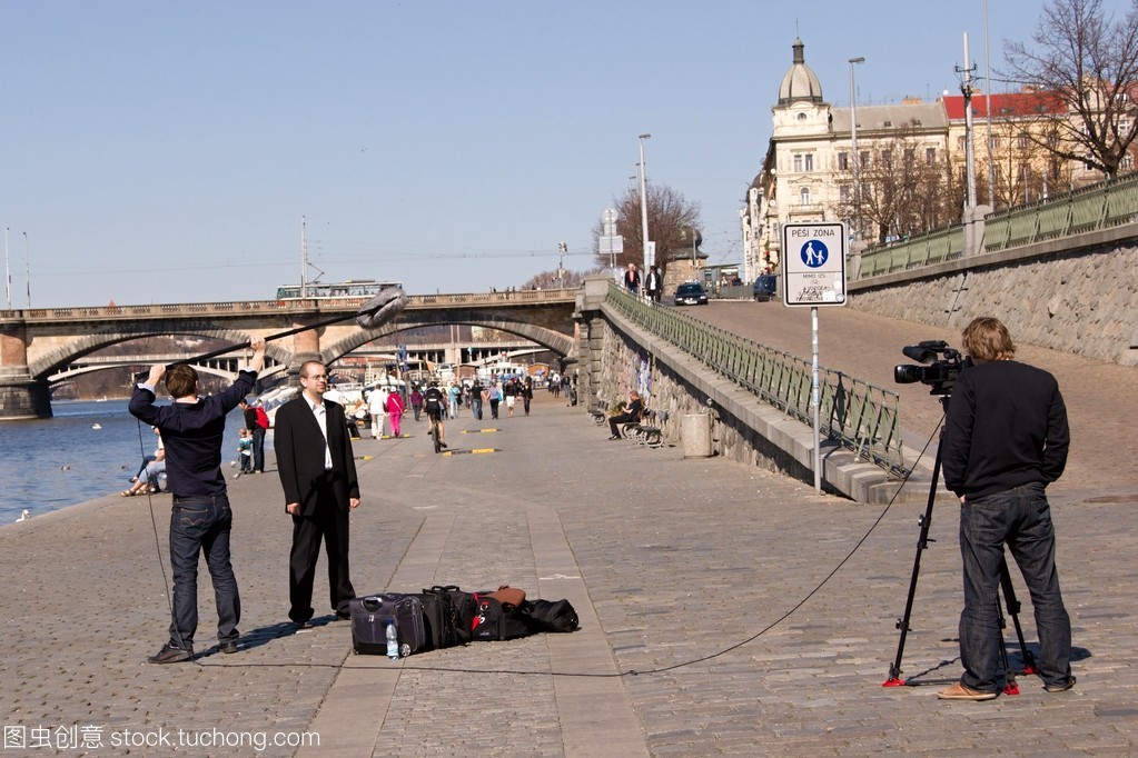 Three-member television staff filming in Prague on the bank of Vltava river